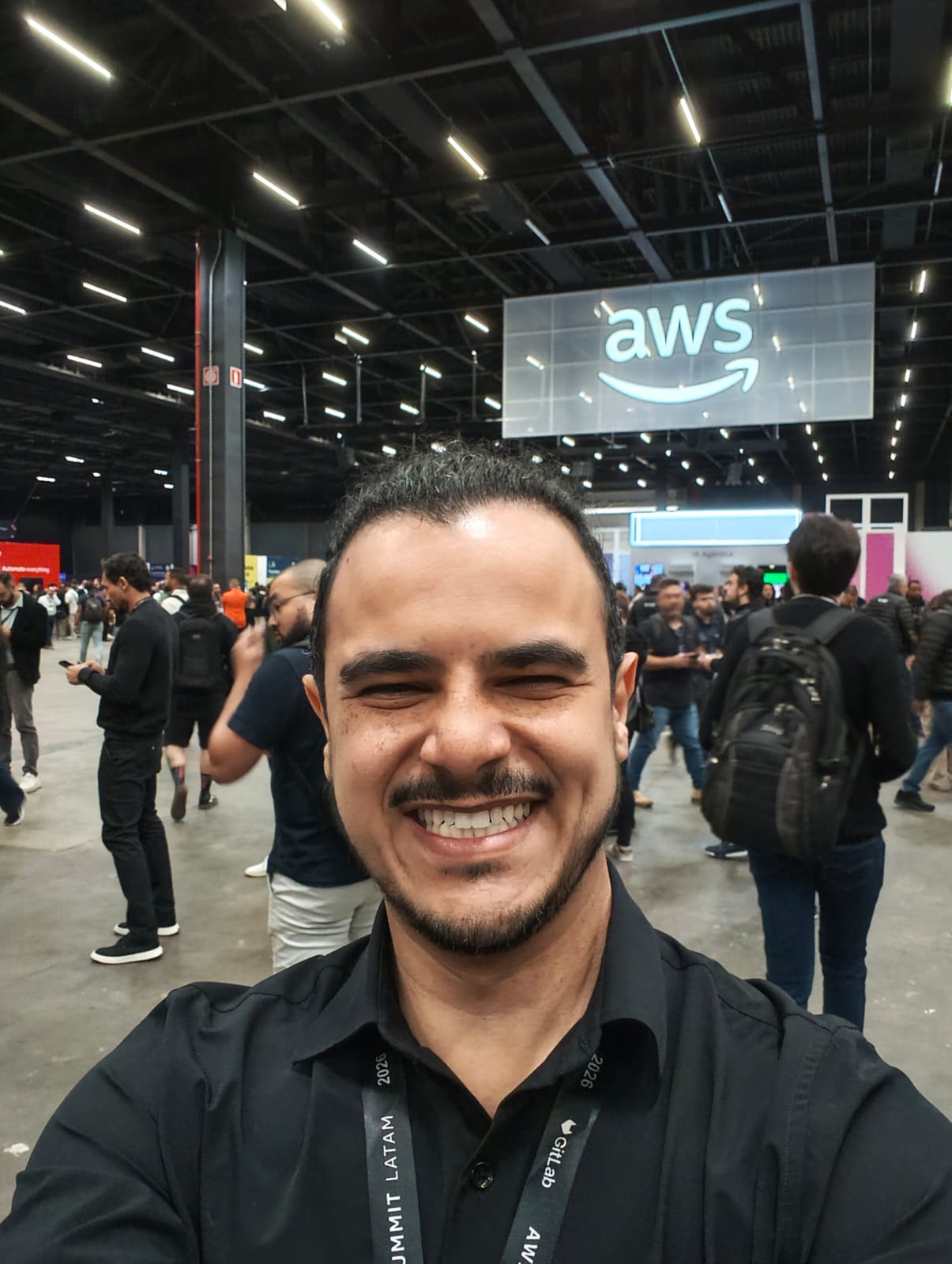Lucas Lascasas no chão de exposição do AWS Summit 2026, com o letreiro da AWS ao fundo